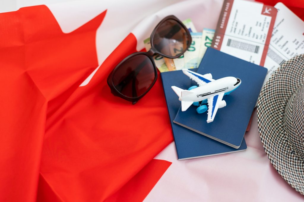 Flag of Canada with passport and toy airplane